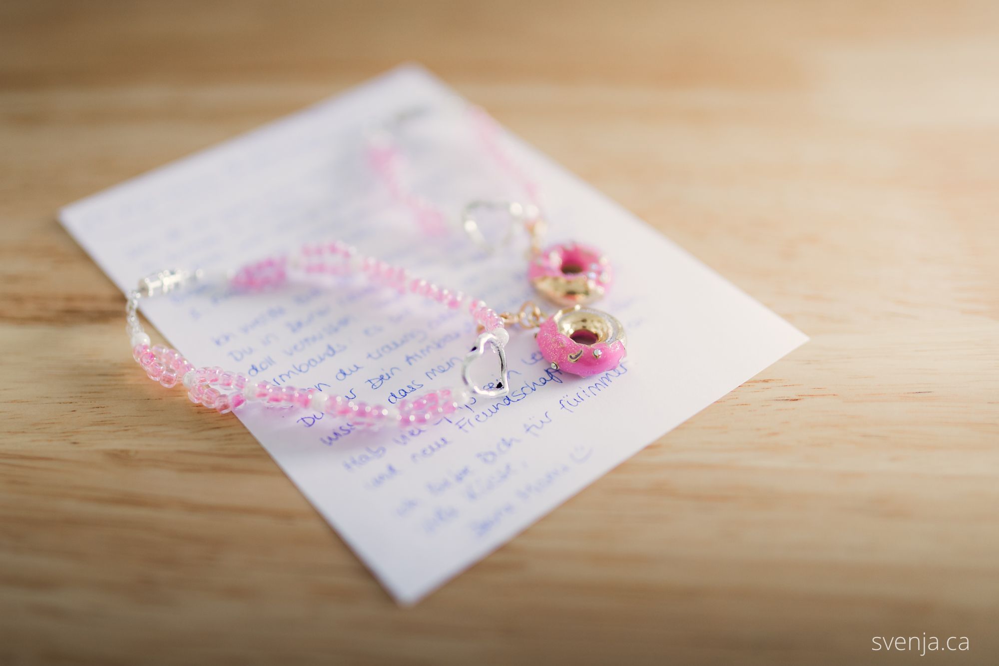 two pink bracelets lay on top of a handwritten note