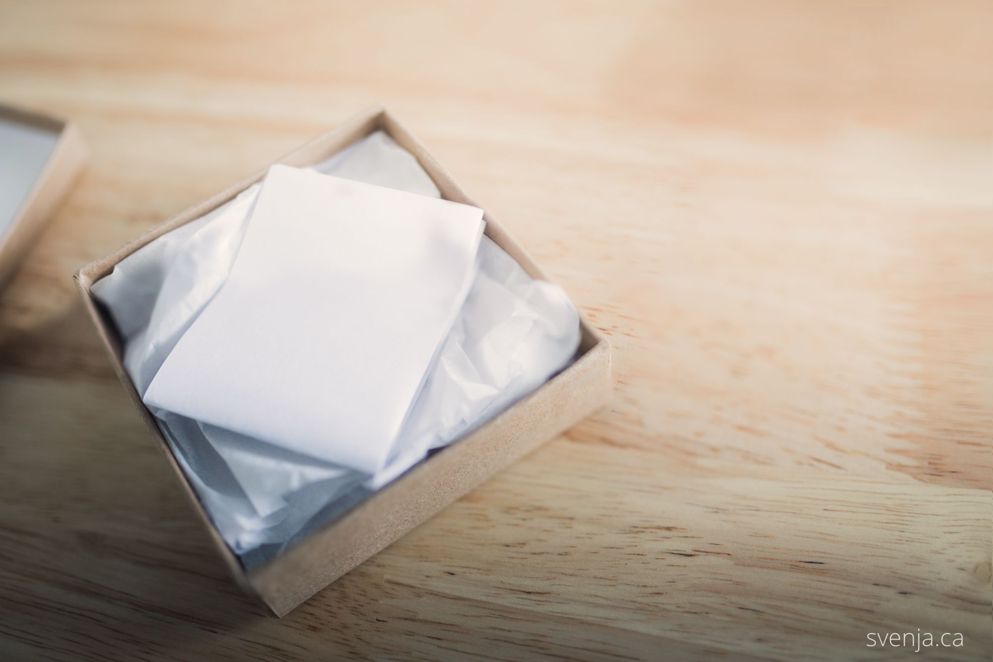 a partially opened box sits on a table with a folded note laying on top of it