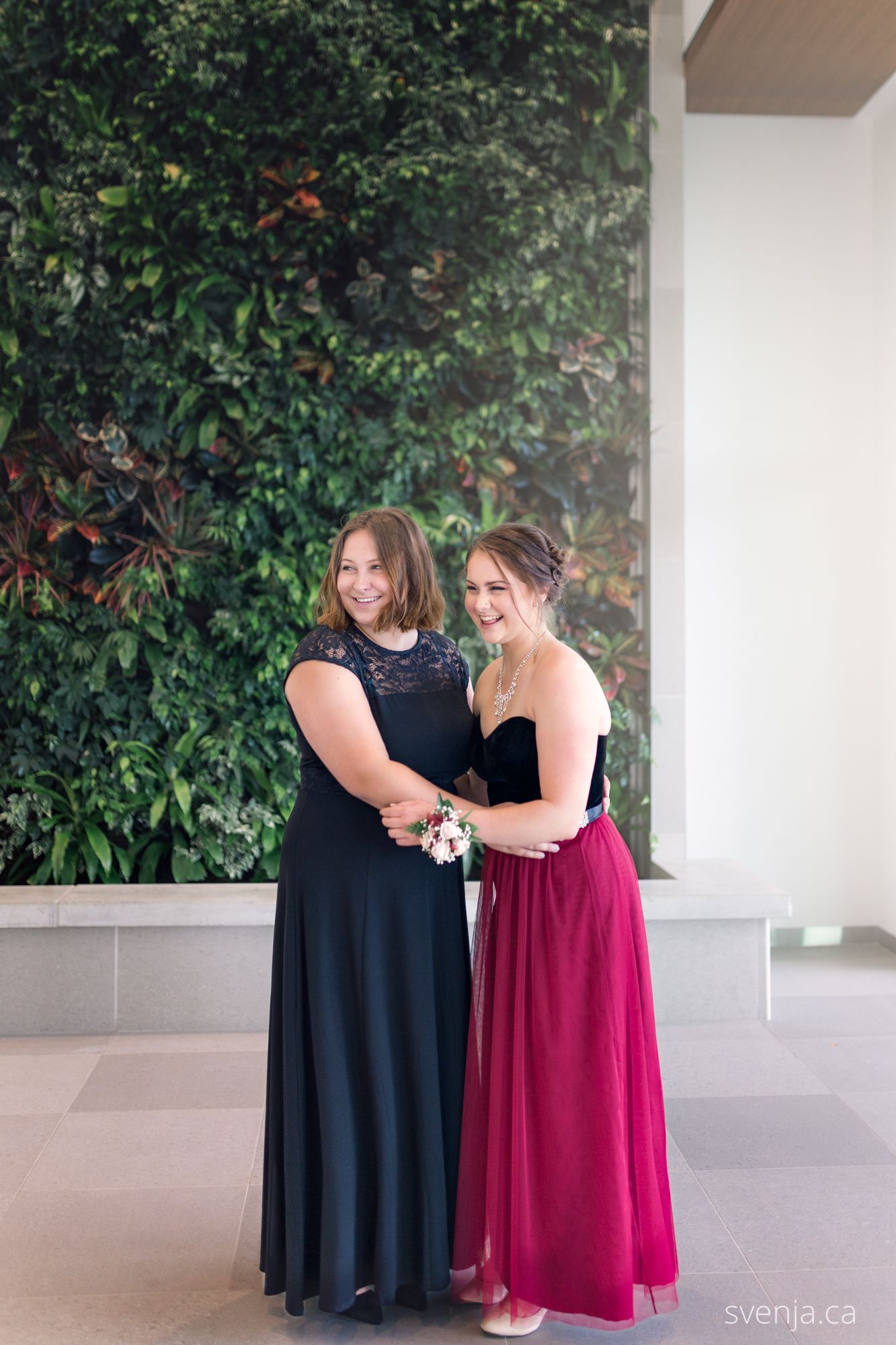 two sisters in front of green plant wall