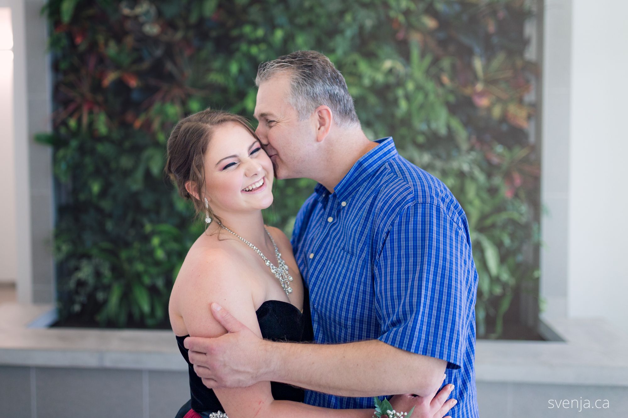 dad daughter in front of a green plant wall