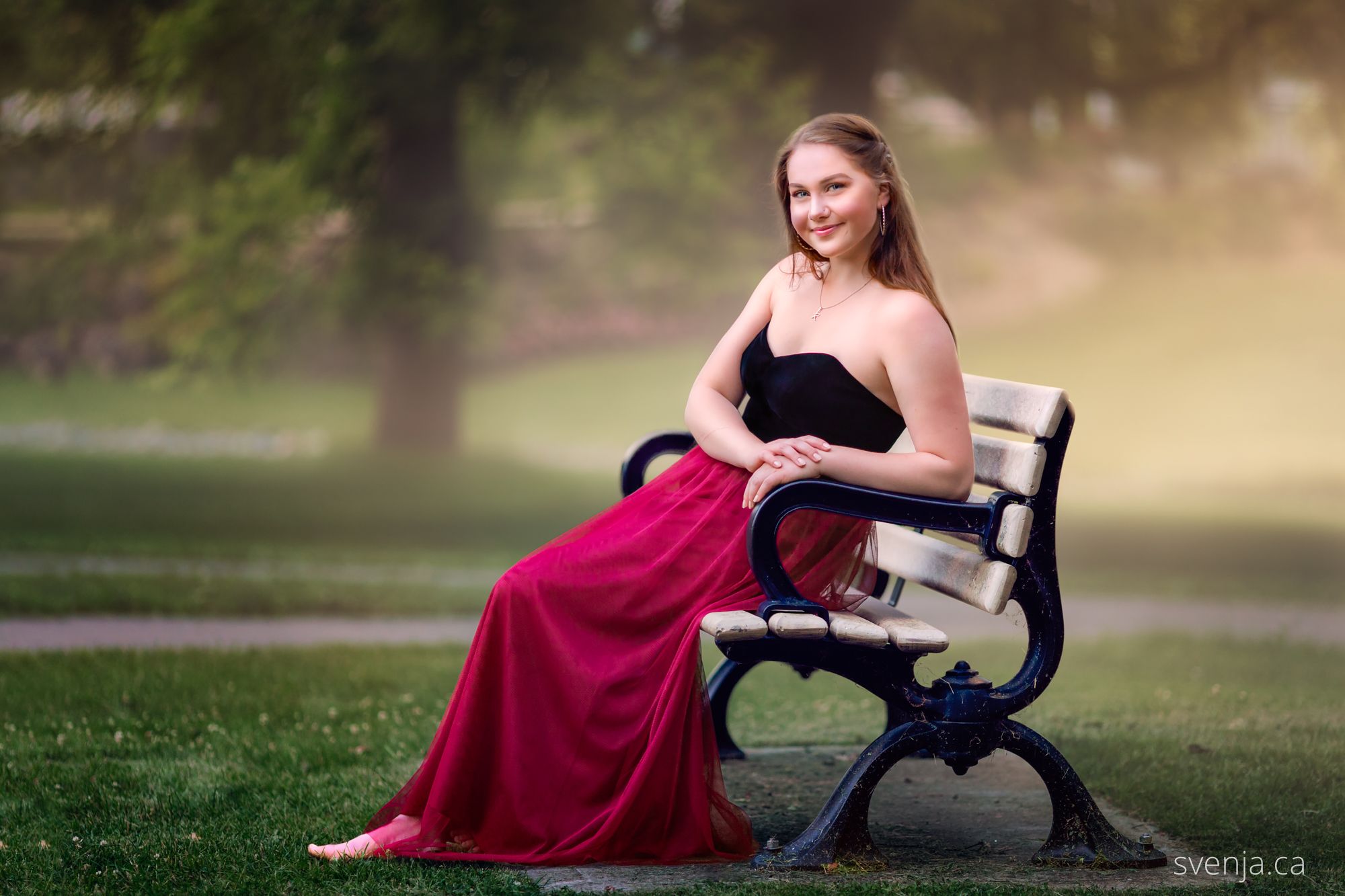 young woman sitting on a bench wearing a dress and smiling