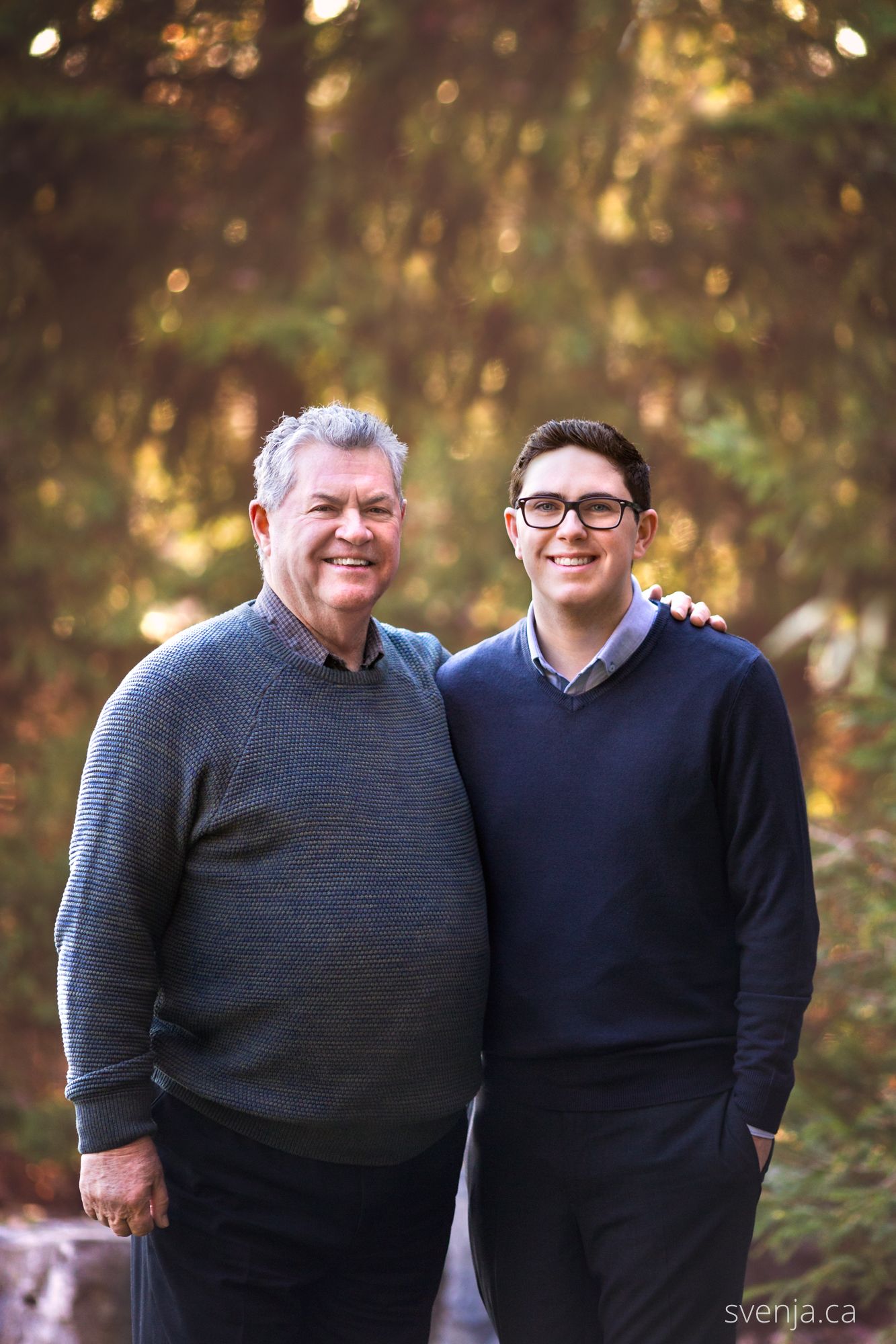 father and son stand in front of forest