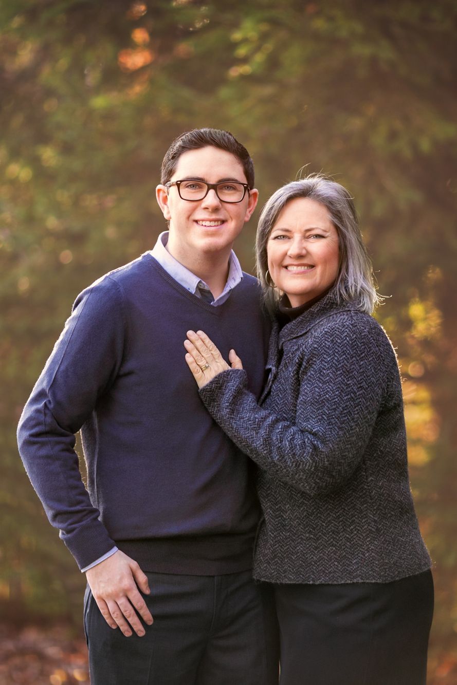 son and mother stand in front of a forest