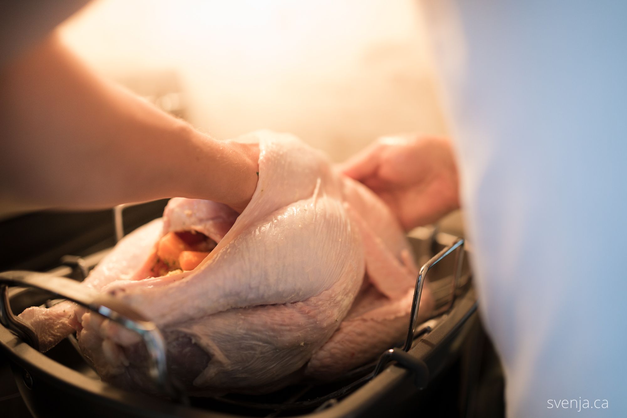 a turkey being buttered and stuffed by a hand