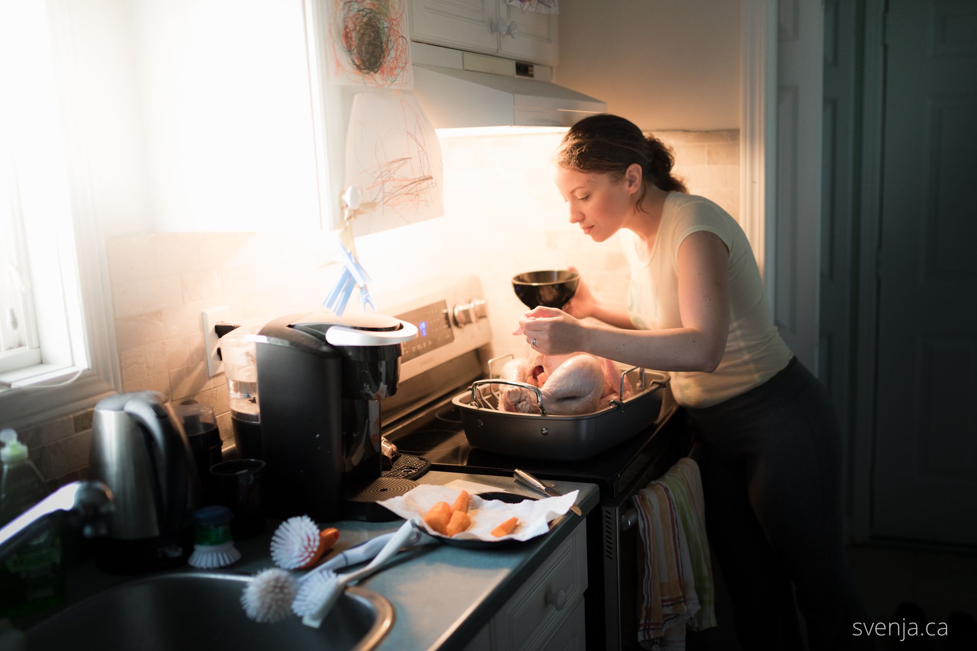 woman seasoning a turkey in a kitchen