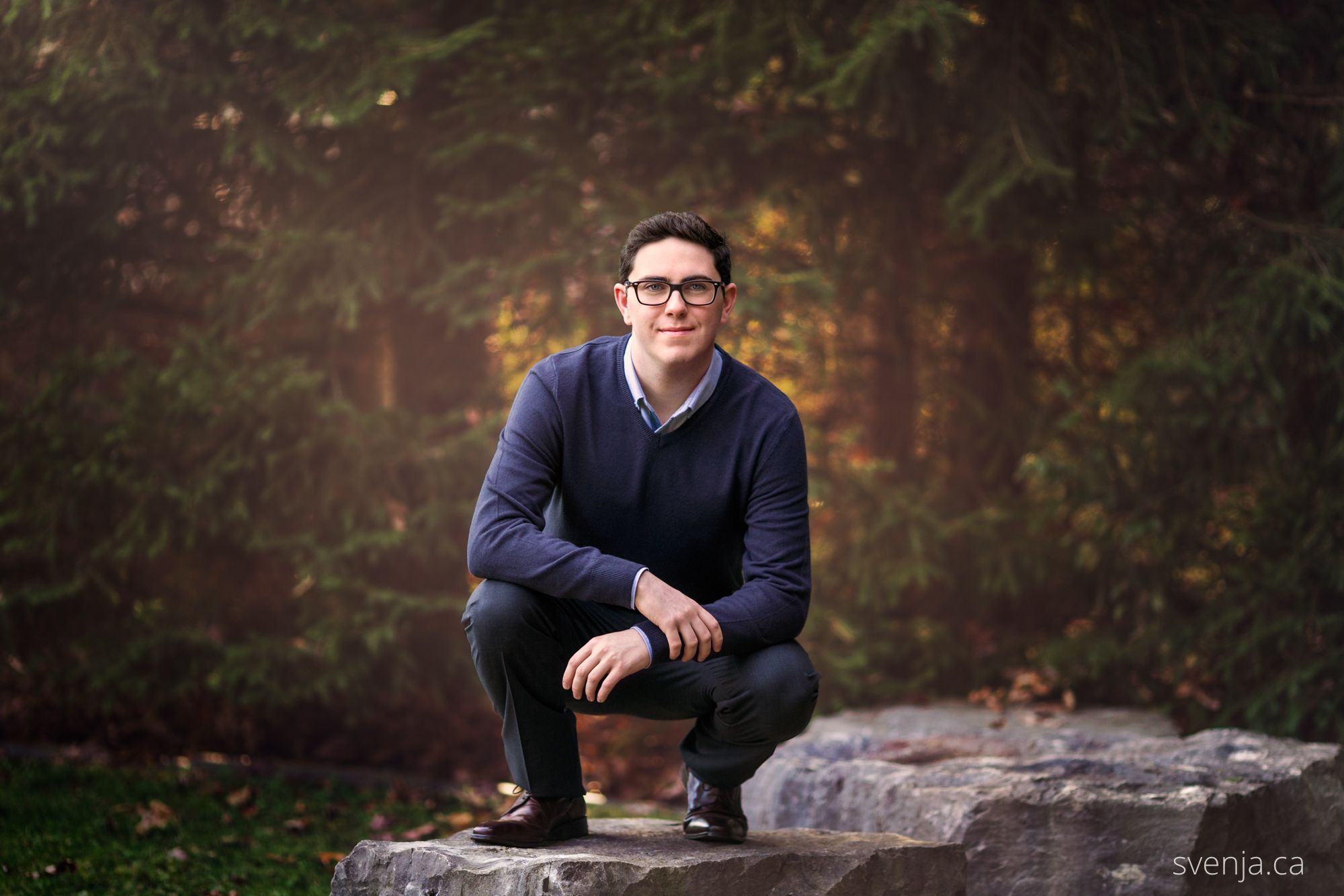 portrait of man crouching on a rock