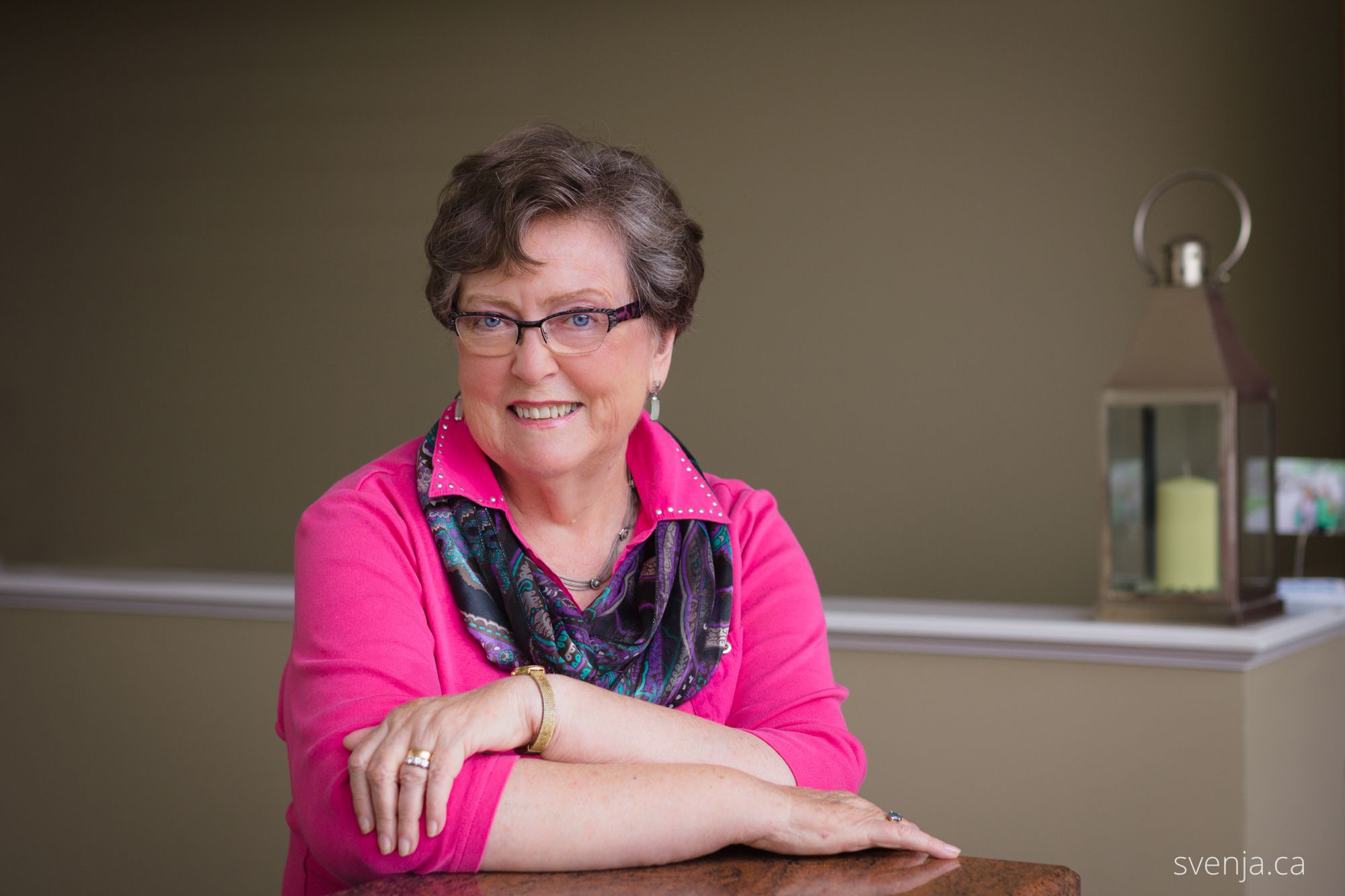 A woman folders her arms, smiling at the camera